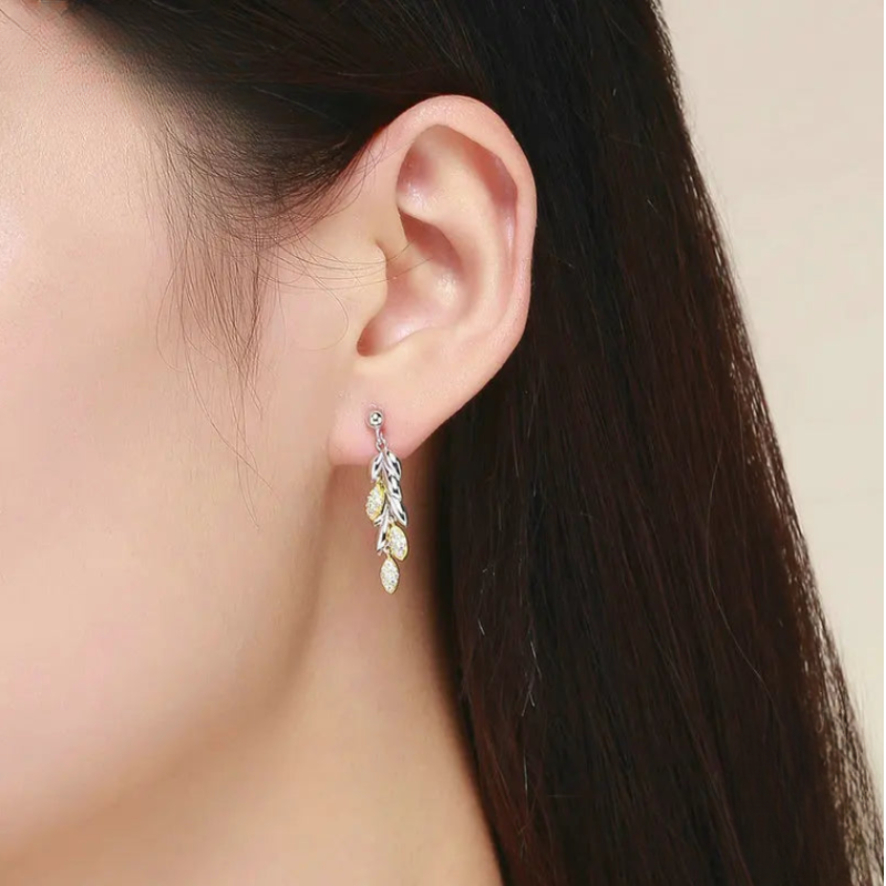 model wearing sterling silver wheat leaves drop earrings in mixed gold and white colours and crafted clear stones