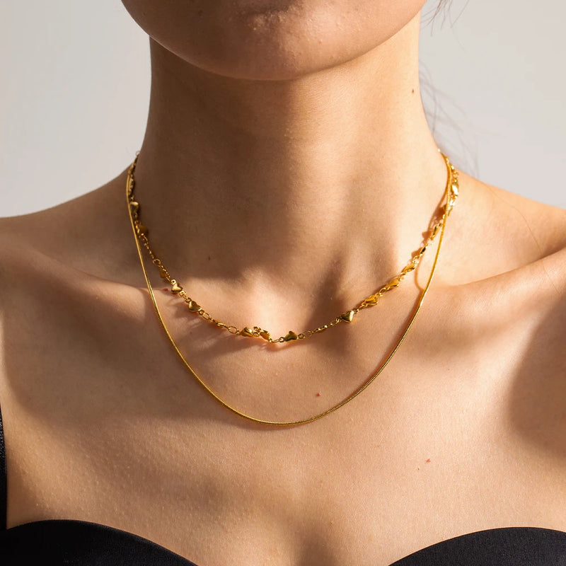 Model wearing Layered Love Necklace in Waterproof 18K Gold-Plated Stainless Steel with heart chocker 37cm and a snake necklace 41.5cm and 5cm extension