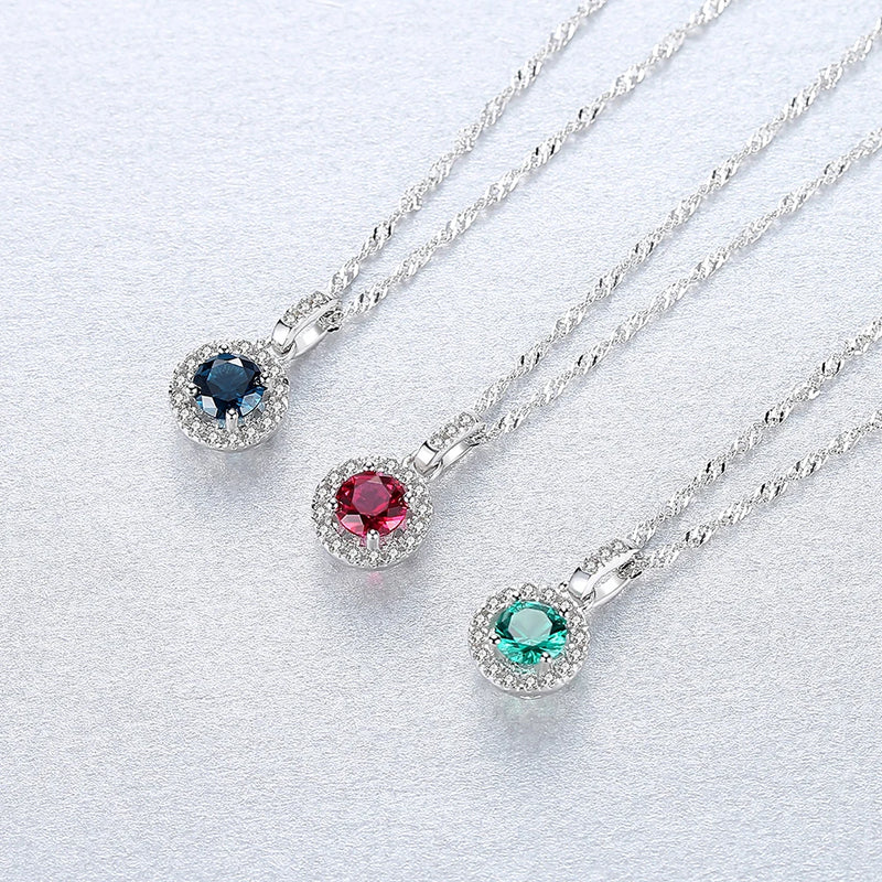 three Sterling Silver Halo Pendant Necklaces in Silver  and blue green or red stones displayed side by side