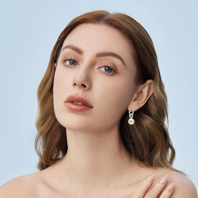 model wearing sterling silver pearl drop earrings with clear stones all over in white gold plating