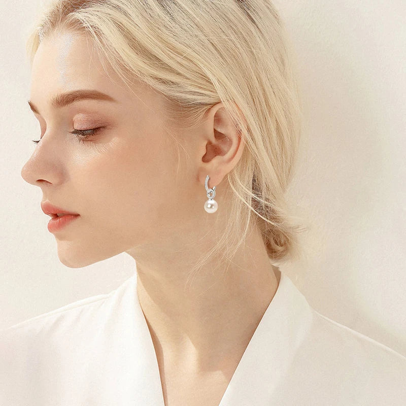 model wearing sterling silver pearl drop earrings with clear stones all over in white gold plating